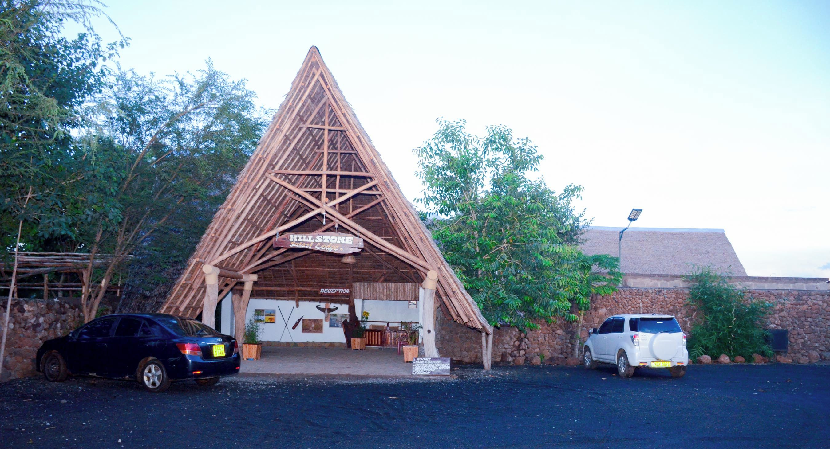 A safari lodge with a triangular roof structure, a reception area, and a stone wall.