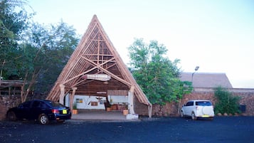 Una struttura tipo lodge safari con tetto a forma triangolare, un'area reception e un muro in pietra.