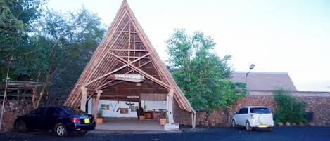 Un lodge de safari con estructura de techo triangular, una zona de recepción y un muro de piedra.