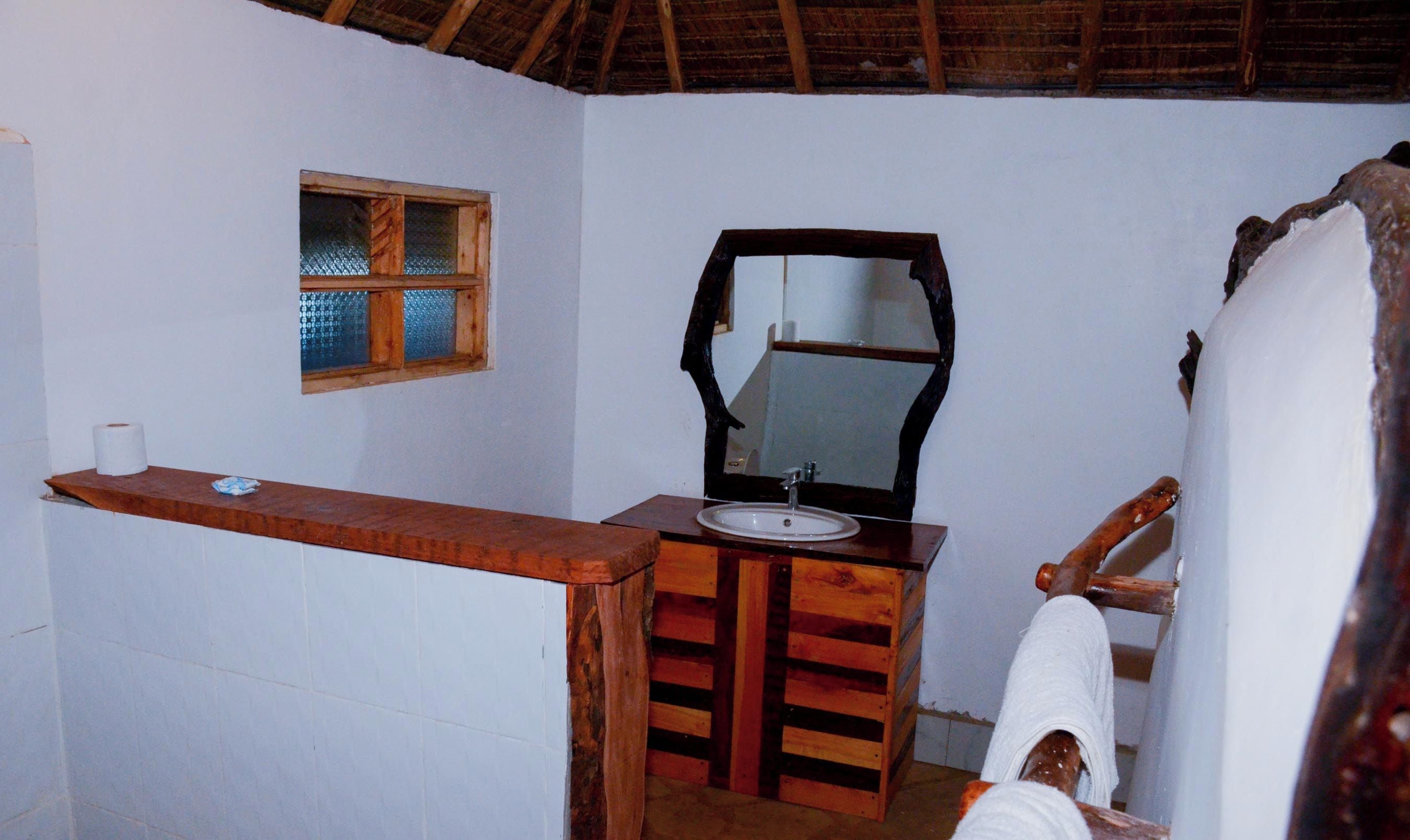 Un baño con tocador de madera, un lavabo, un espejo y una ventana con marco de madera.