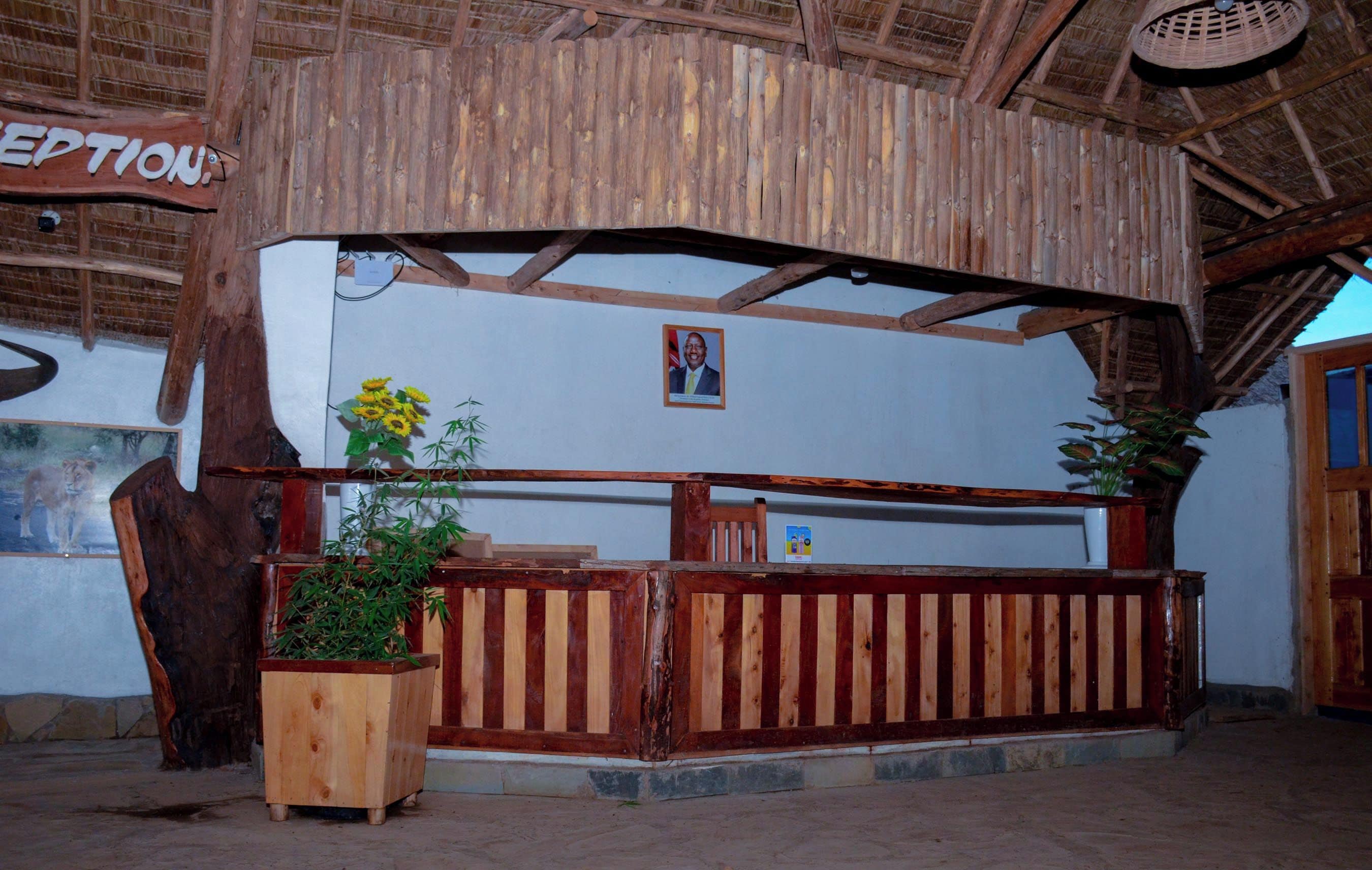 A reception area with a wooden reception desk, a framed photo on the wall, and a potted plant.