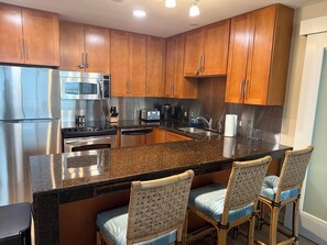 A modern kitchen with stainless steel appliances, wooden cabinets, and a granite countertop.