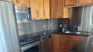 Eine moderne Küche mit Edelstahlgeräten, Holzschränken und einer Arbeitsplatte aus Granit.