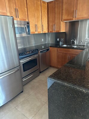A modern kitchen with stainless steel appliances, wooden cabinets, and a granite countertop. - Enjoy 25% off per night for stays at the beach through the end of 2026. (Biloxi)