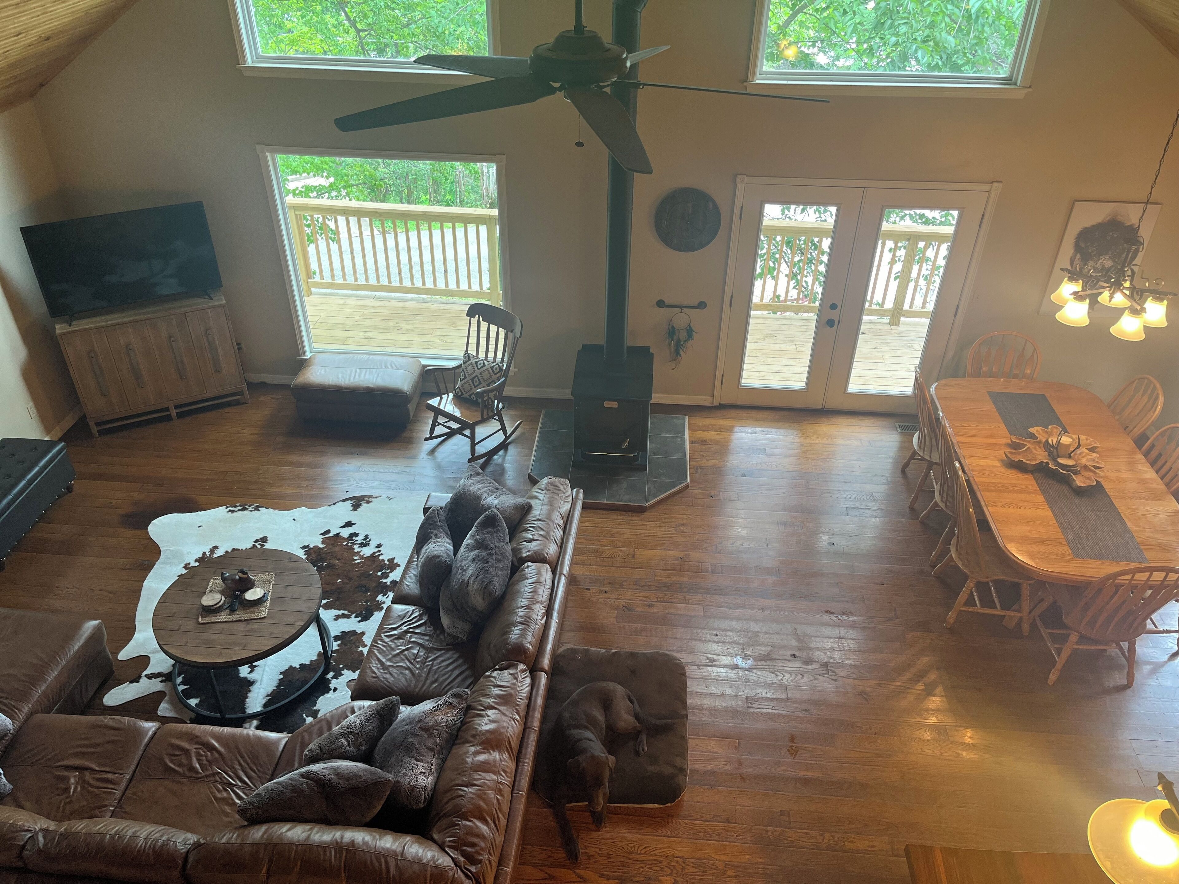 Uma sala ampla com sofá de couro, mesa de jantar de madeira e lareira.