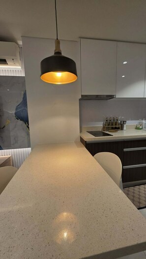 Una cocina con salpicadero de mármol, una lámpara colgante y muebles de cocina modernos.