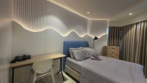 Una habitación de hotel moderna con cama, escritorio, silla y armario.
