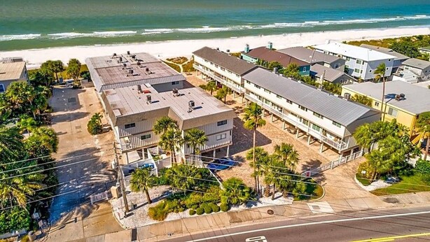 A coastal hotel with multiple buildings, a beach view, and a parking area. - Gulfside Villas Unit 11... Steps to the Beach, Heated Pool Beautiful Townhome (Indian Rocks Beach)