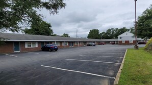 A motel with a parking lot, a brick building, and a grassy area. - Town & Country (Seekonk)