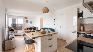 A modern kitchen with a wooden countertop, integrated appliances, and a dining area with a sofa and chairs.