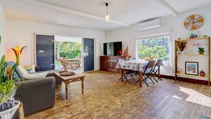 Un grand espace de vie doté d’un plancher en bois, d’une table à manger avec des chaises, d’un canapé et d’un téléviseur.