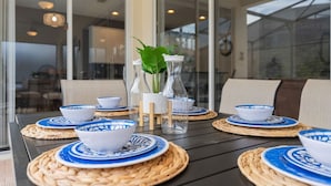 Ein Tisch gedeckt mit blau-weißen Tellern, klaren Glasflaschen und einem Blumentopf.