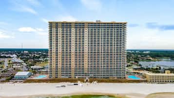 A high-rise hotel with a beach view, multiple balconies, and a pool area.