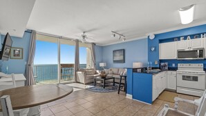 A room with a balcony, a dining area, a kitchen, and a living area. - Breathtaking Beachfront Condo, By Pier Park, Pools (Panama City Beach)