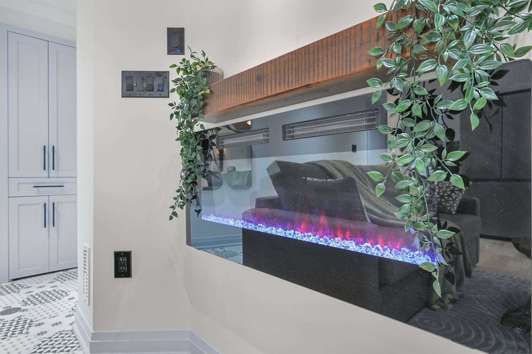 A modern living room with a large aquarium, white cabinets, and a wooden shelf.