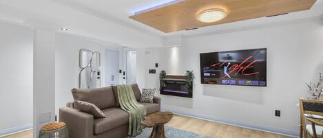 A modern living room with a brown sofa, a wooden coffee table, and a flat-screen TV mounted on the wall.