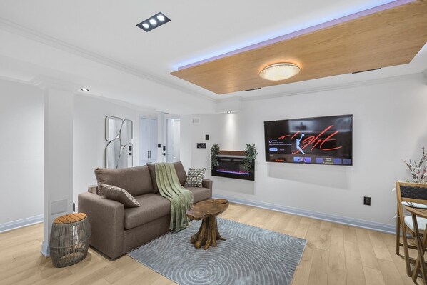 Un salon moderne avec un canapé marron, une table basse en bois et un téléviseur à écran plat fixé au mur.