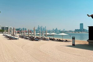 Relax on the beach with sun loungers and umbrellas, steps from the city's vibrant skyline.