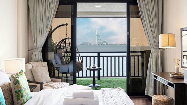 Une chambre d’hôtel avec un lit, une chaise, une petite table et une vue sur un pont.
