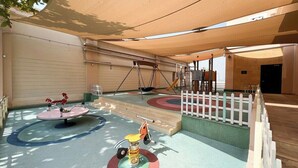 Un espace de jeux pour enfants avec des balançoires, une bascule et un manège.