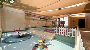 Een speelruimte voor kinderen met schommels, een wipkippen en een draaimolen.