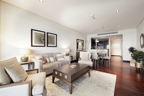 Een moderne woonkamer met een bank, fauteuils, een salontafel, en een eethoek met stoelen en een tafel.