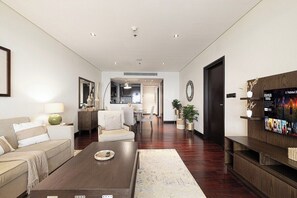 Een moderne woonkamer met een donkerhouten salontafel, een bank en een televisie op een houten dressoir.