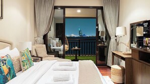 Une chambre d’hôtel avec un lit, une chaise, une petite table, un téléviseur et une vue sur le paysage urbain.