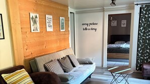 A modern living room with a wooden wall, a sofa, a brown armchair, and a bench.