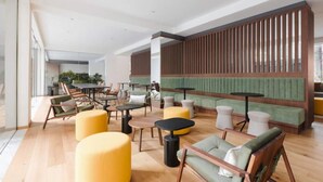 Een moderne lounge met zithoek, een groene gestoffeerde bank en een houten scheidingswand.