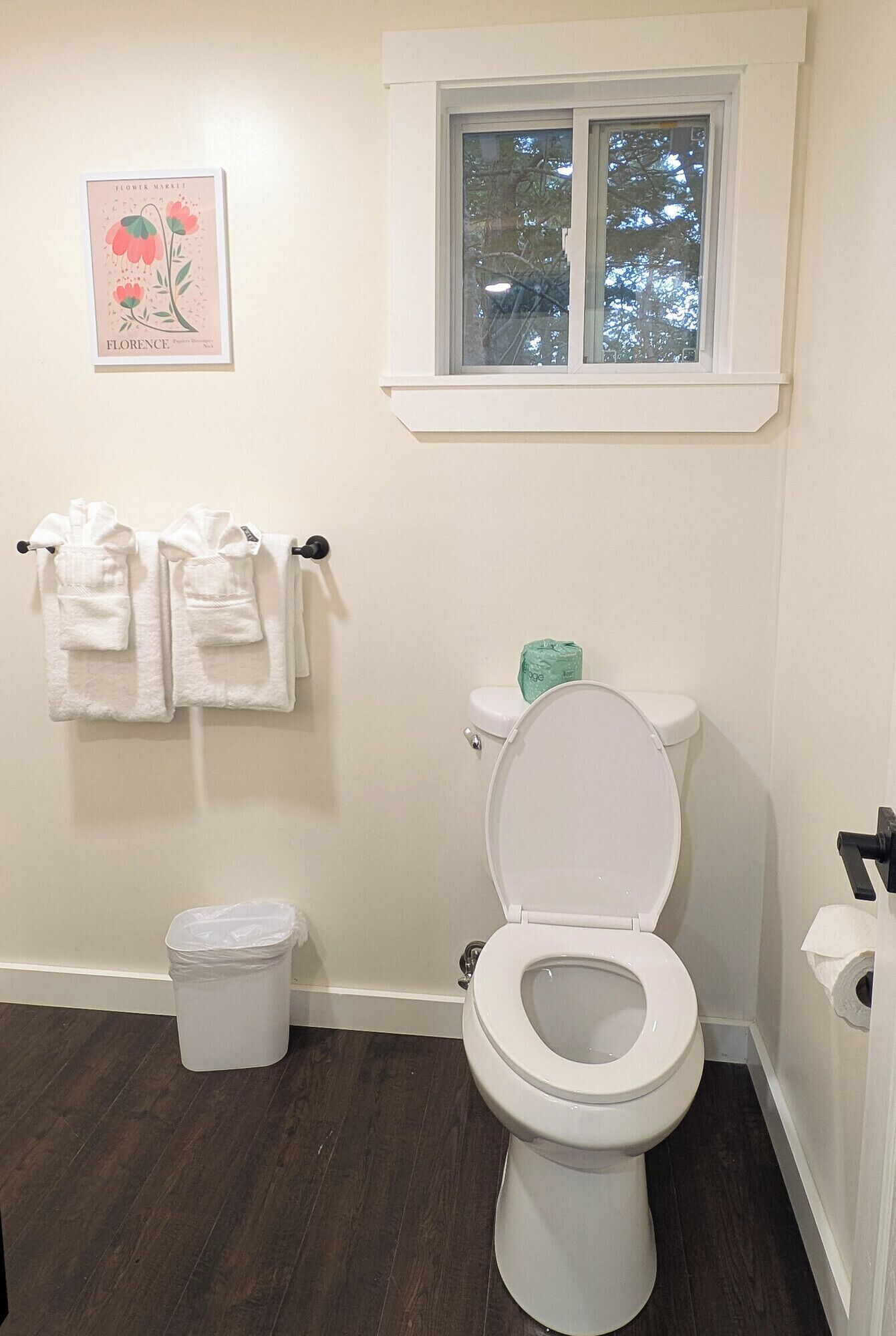 Et badeværelse med toilet, skraldespand og et vindue.