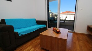 Una sala de estar con un sofá marrón oscuro, una manta azul y una mesa de centro de madera con fruta.