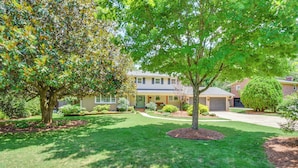 A residential property with a well-maintained lawn, mature trees, and a two-story house with a garage. - Spacious Taylors Home ~ 5 Mi to Dtwn Greenville! (Taylors)
