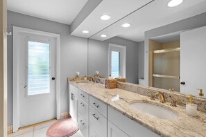 Une salle de bain moderne avec deux lavabos, un grand miroir et un meuble-lavabo avec des tiroirs.