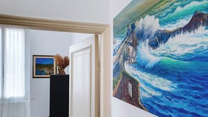 A hallway with a framed coastal landscape painting and a door leading to another room. - Private parking & air conditioning, 10 minutes walk from center (Genoa)