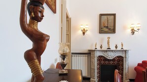 A room with a wooden sculpture, a fireplace with decorative items, wall sconces, and a framed painting. - Private parking & air conditioning, 10 minutes walk from center (Genoa)