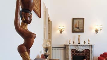 Una stanza con una scultura in legno, un caminetto decorato e quadri appesi alle pareti.
