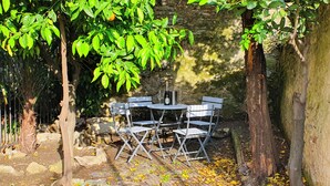 A table set outdoors with a bottle and glasses, surrounded by trees and a stone wall. - Private parking & air conditioning, 10 minutes walk from center (Genoa)