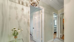 A hallway with a glass table, a white door, and a chandelier. - Orange Grove (Melbourne)
