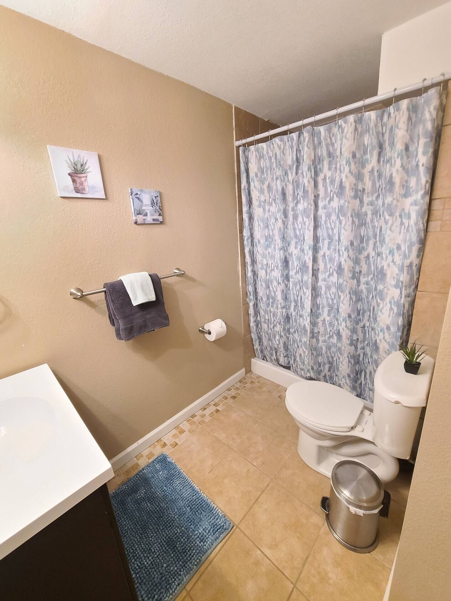 Une salle de bain équipée de toilettes, d’un lavabo, d’un rideau de douche et d’une petite poubelle.