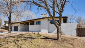 A modern single-story house with a garage, a covered patio, and a large lawn. - Entire guest suite in Colorado Springs, Colorado (Colorado Springs)