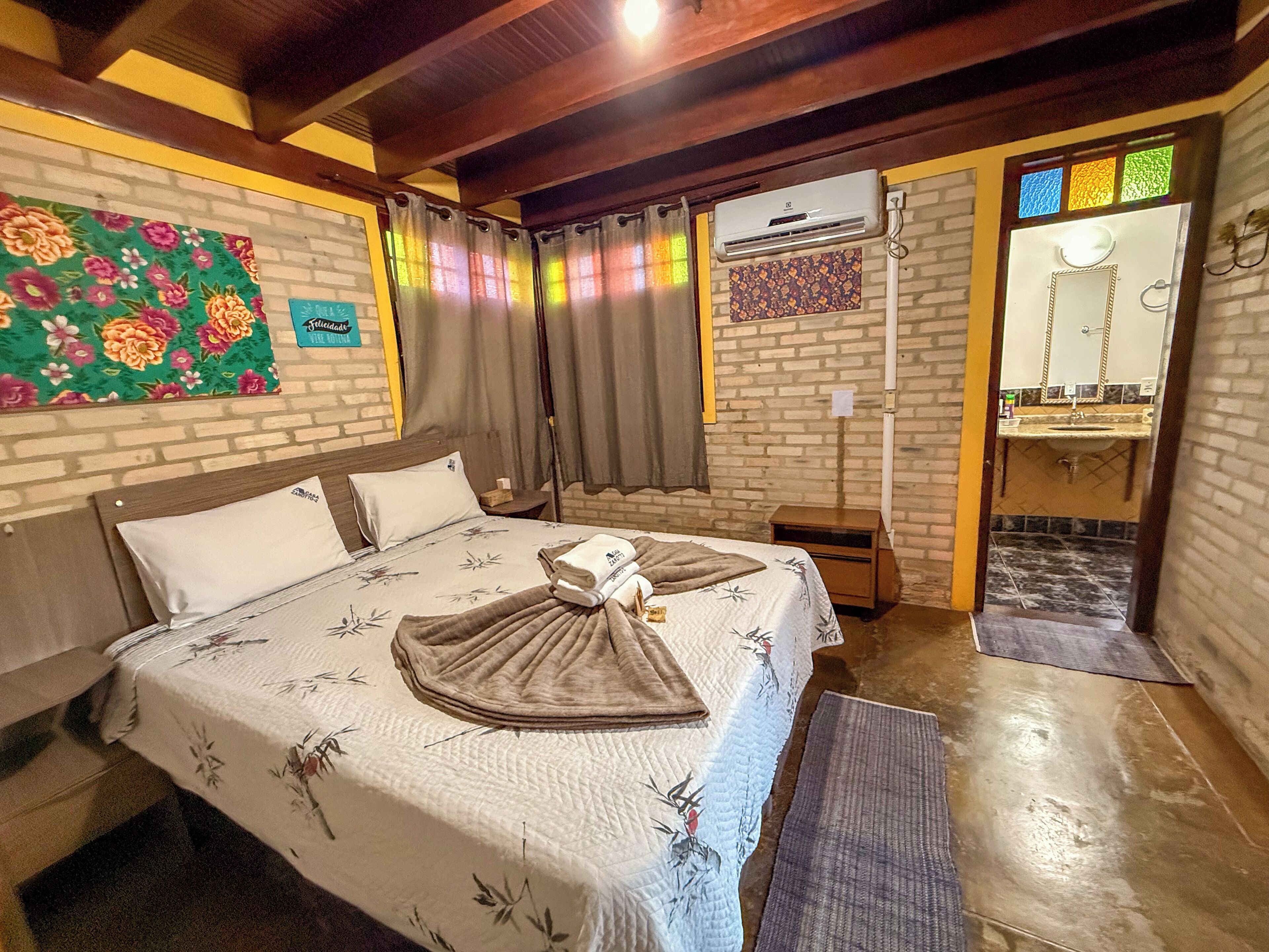 A hotel room with a bed, a nightstand, a mirror, and a window with curtains.