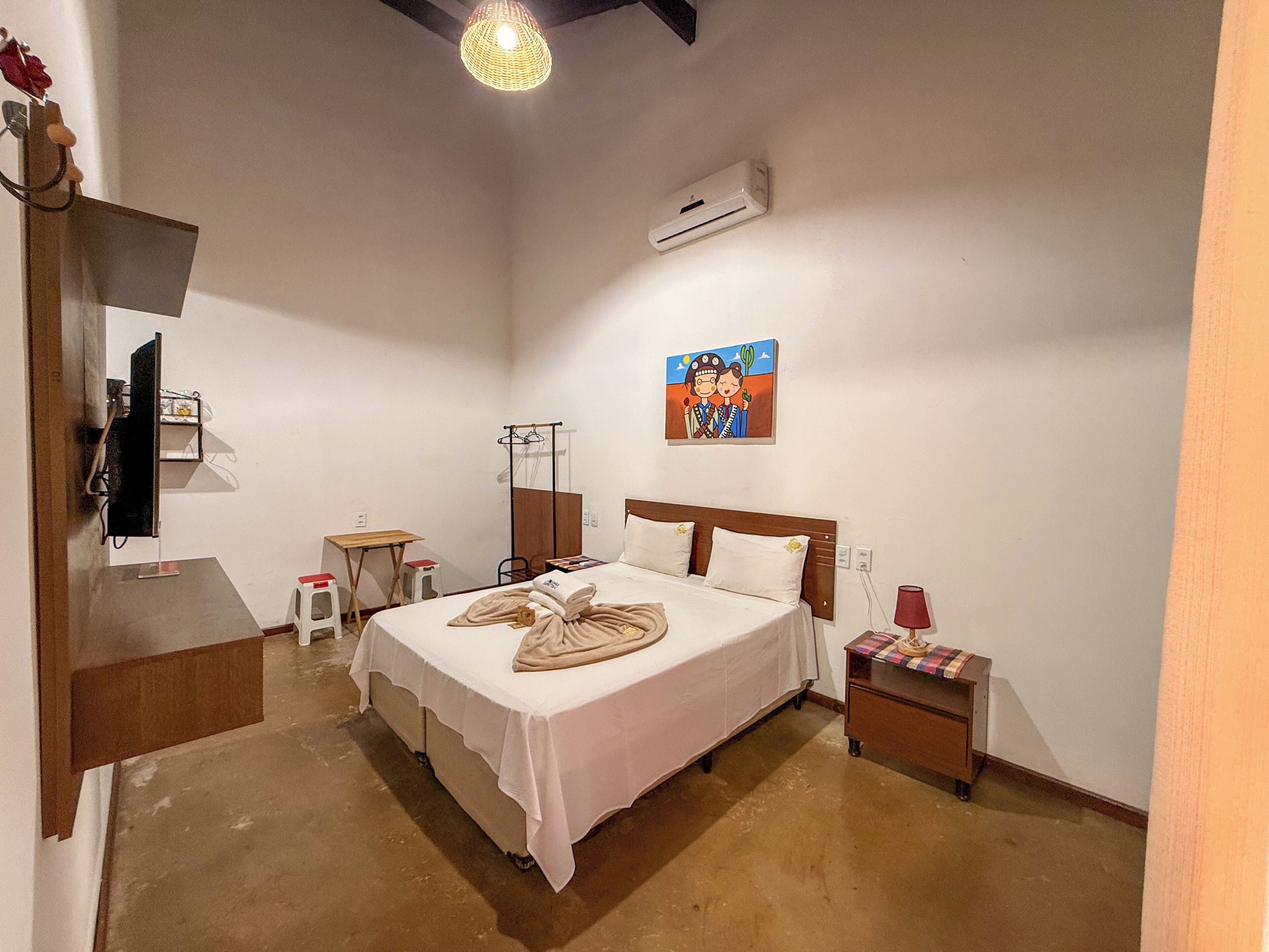 A bedroom with a bed, bedside table, and a wall-mounted air conditioner.