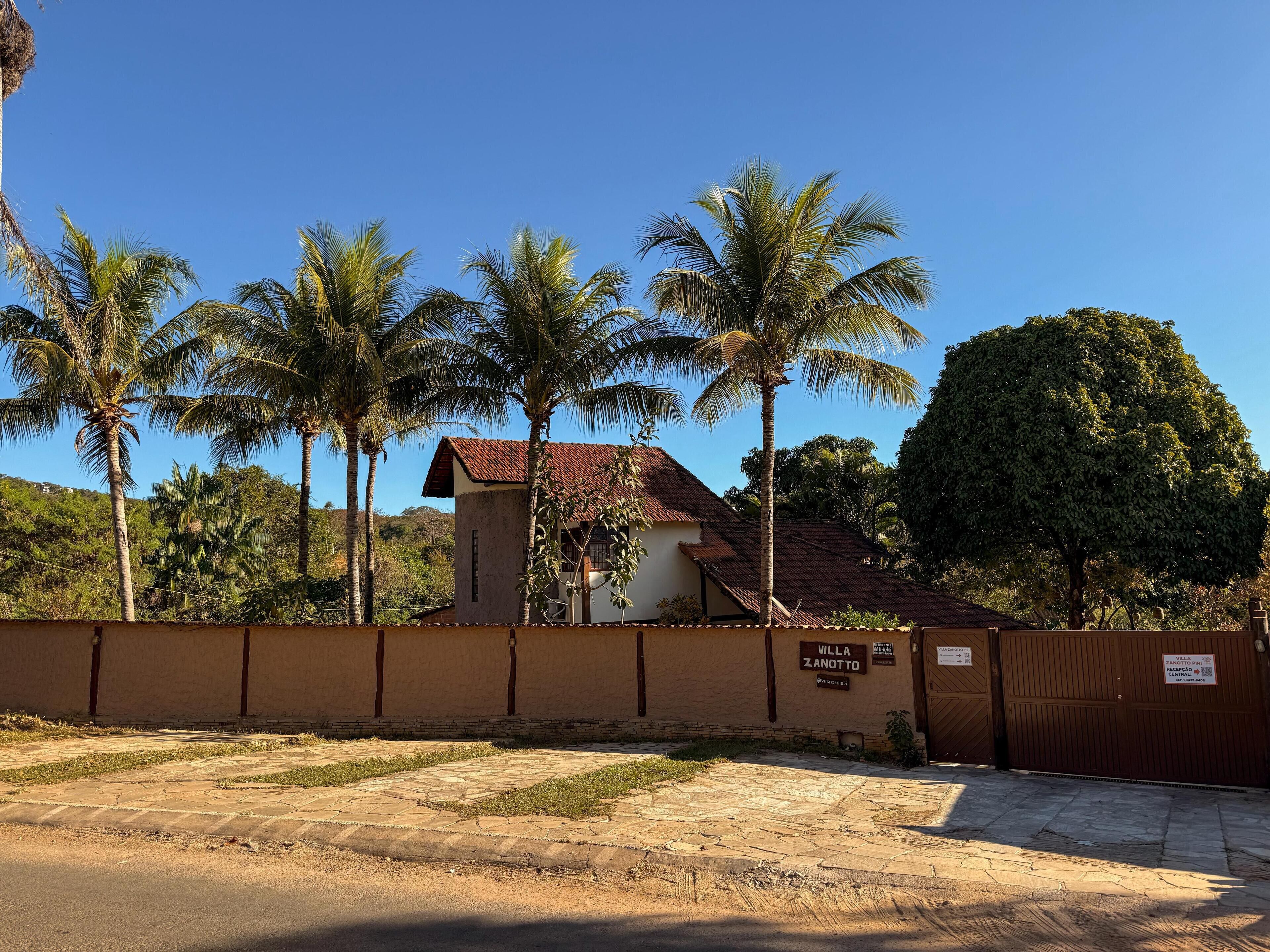 A villa named "Villa Zanotto" with a tiled roof, surrounded by palm trees and a stone pathway leading to the entrance.