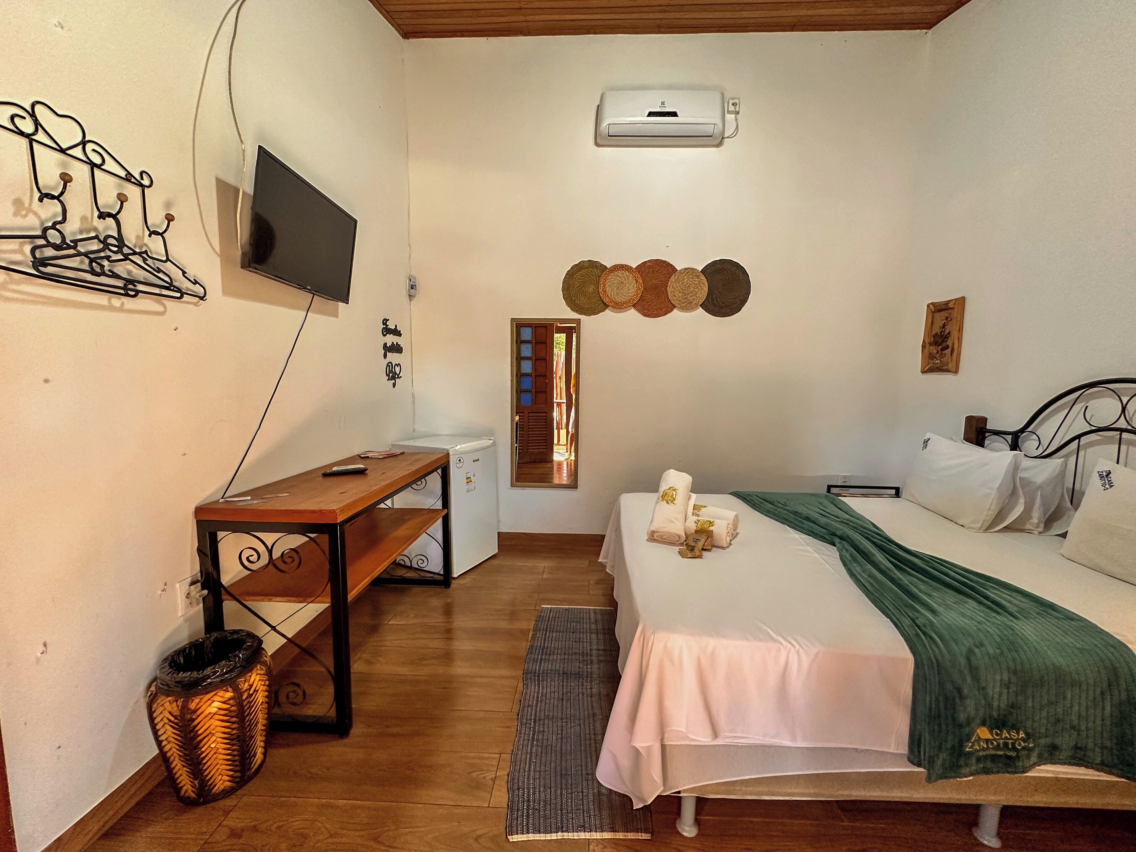 A bedroom with a bed, a desk, a TV, and a washing machine.