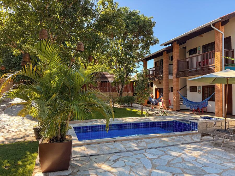 Un área de piscina con suelo de piedra, una hamaca y una planta en maceta.