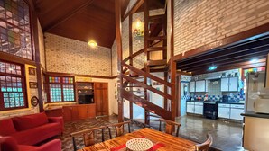 Un restaurante acogedor con una mesa de comedor de madera, sillas rojas y una pared de ladrillo.