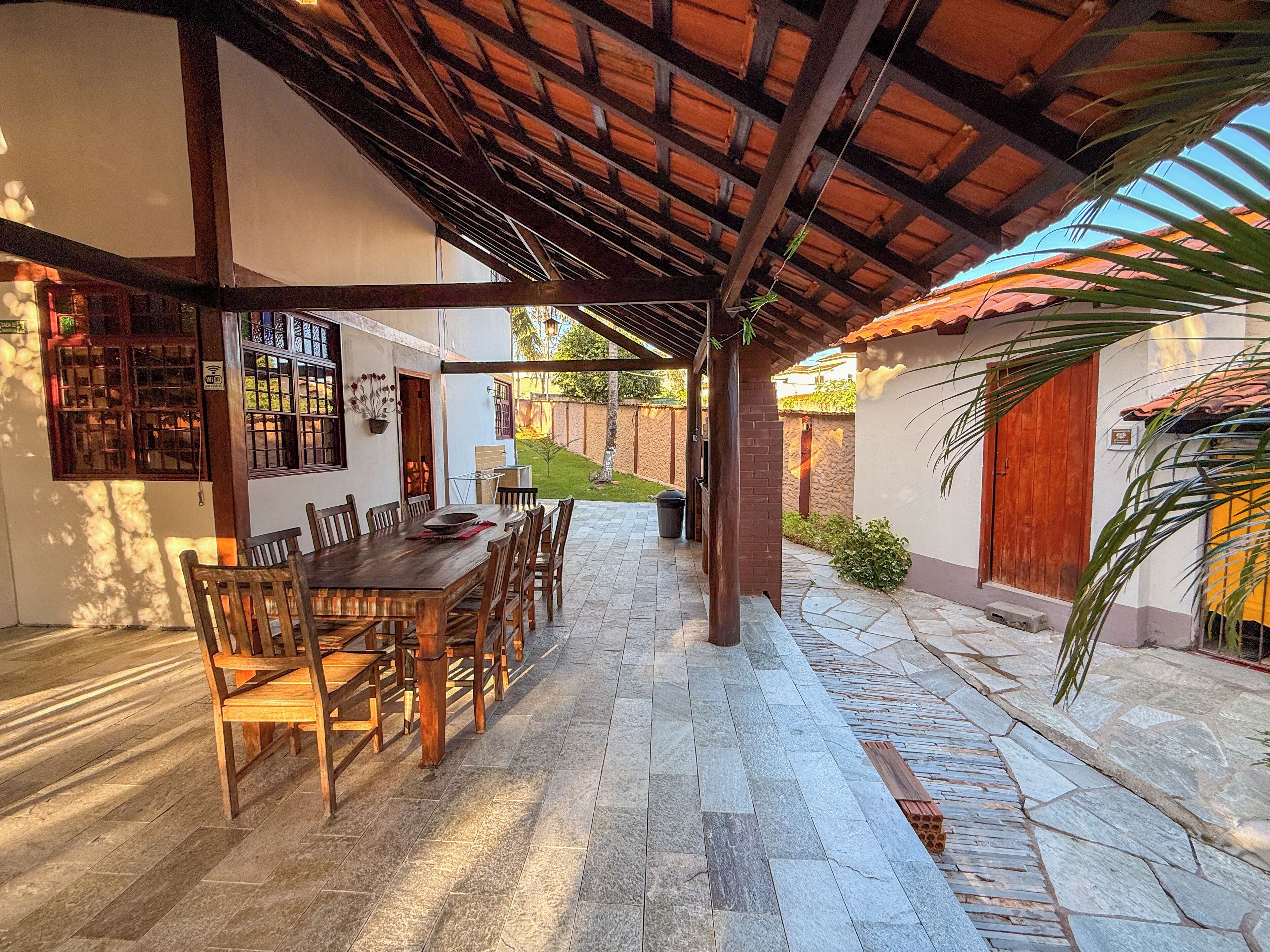 An outdoor patio with a wooden table and chairs, a covered seating area, and a stone pathway.