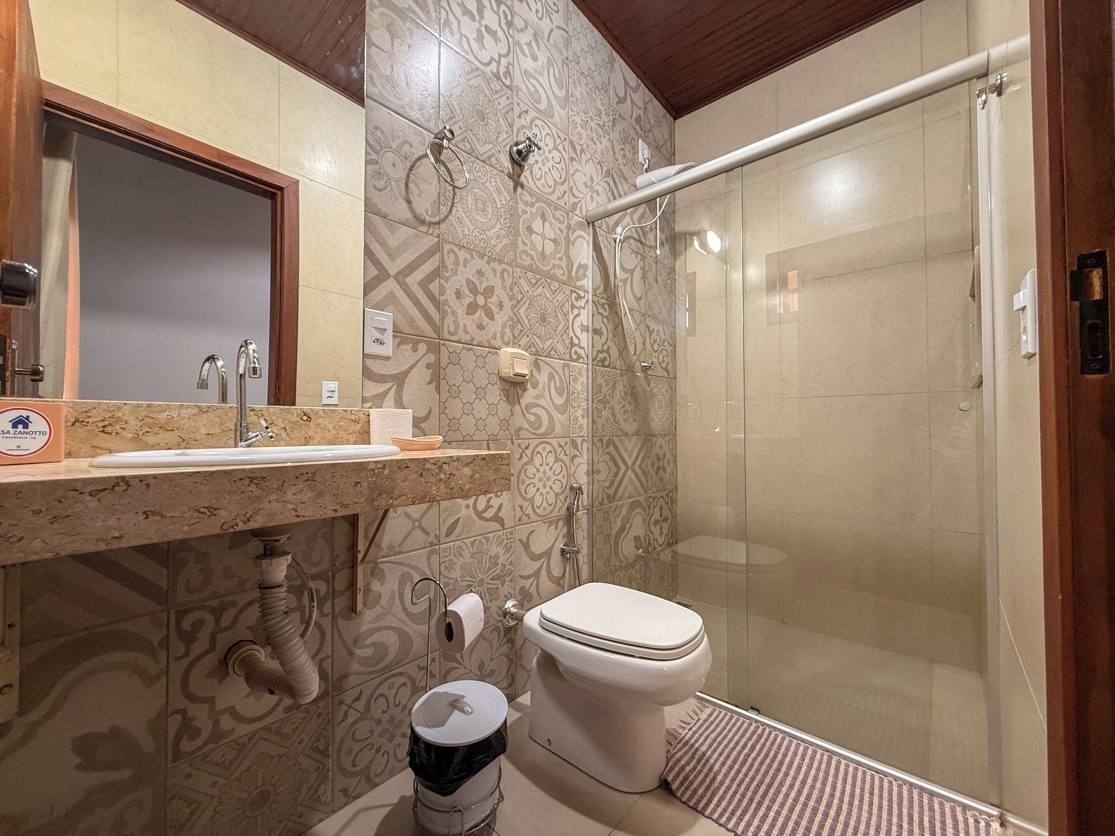 Bagno con doccia, WC, lavandino e porta asciugamani.