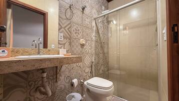 A bathroom with a shower, toilet, sink, and a towel rack.